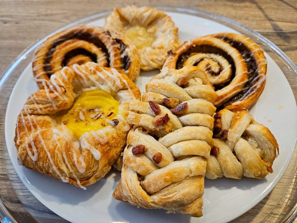 A selection of fresh pastries on a plate - cinnamon swirls, pecan twists and custard pastry